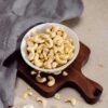 pexels-photo-4499222-4499222 Top view of cashew nuts in a bowl on a wooden cutting board, perfect for healthy snack concepts.