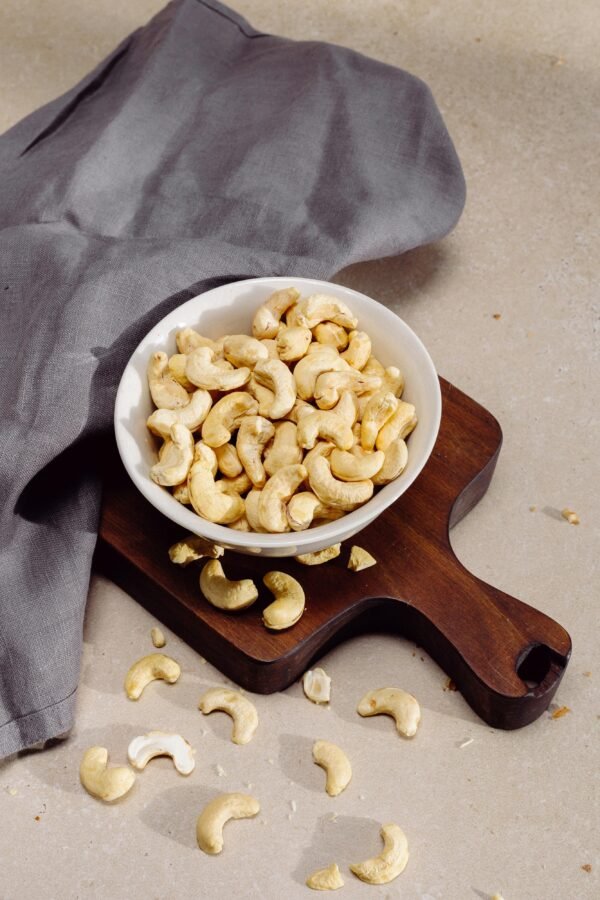 pexels-photo-4499222-4499222 Top view of cashew nuts in a bowl on a wooden cutting board, perfect for healthy snack concepts.
