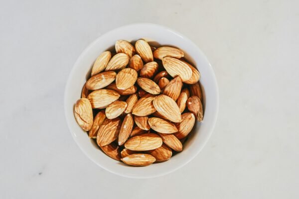 A close-up of raw almonds in a white bowl, highlighting their texture and natural appeal.