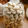 Close-up of pistachios in a glass jar, showcasing healthy snacking options.