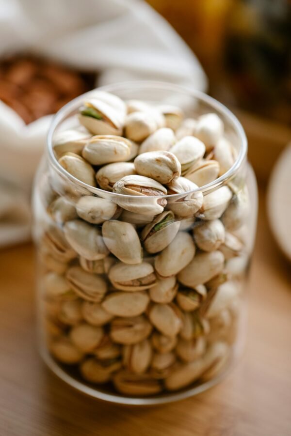 Close-up of pistachios in a glass jar, showcasing healthy snacking options.
