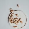 pexels-photo-7421519-7421519 Overhead view of pistachios on a saucer against a neutral background.