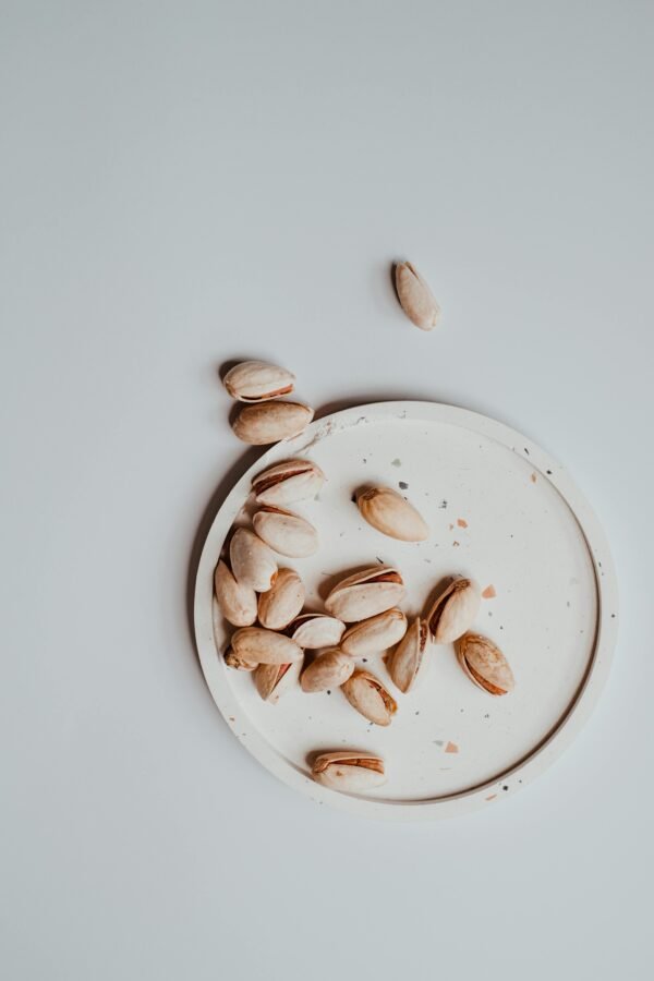 pexels-photo-7421519-7421519 Overhead view of pistachios on a saucer against a neutral background.